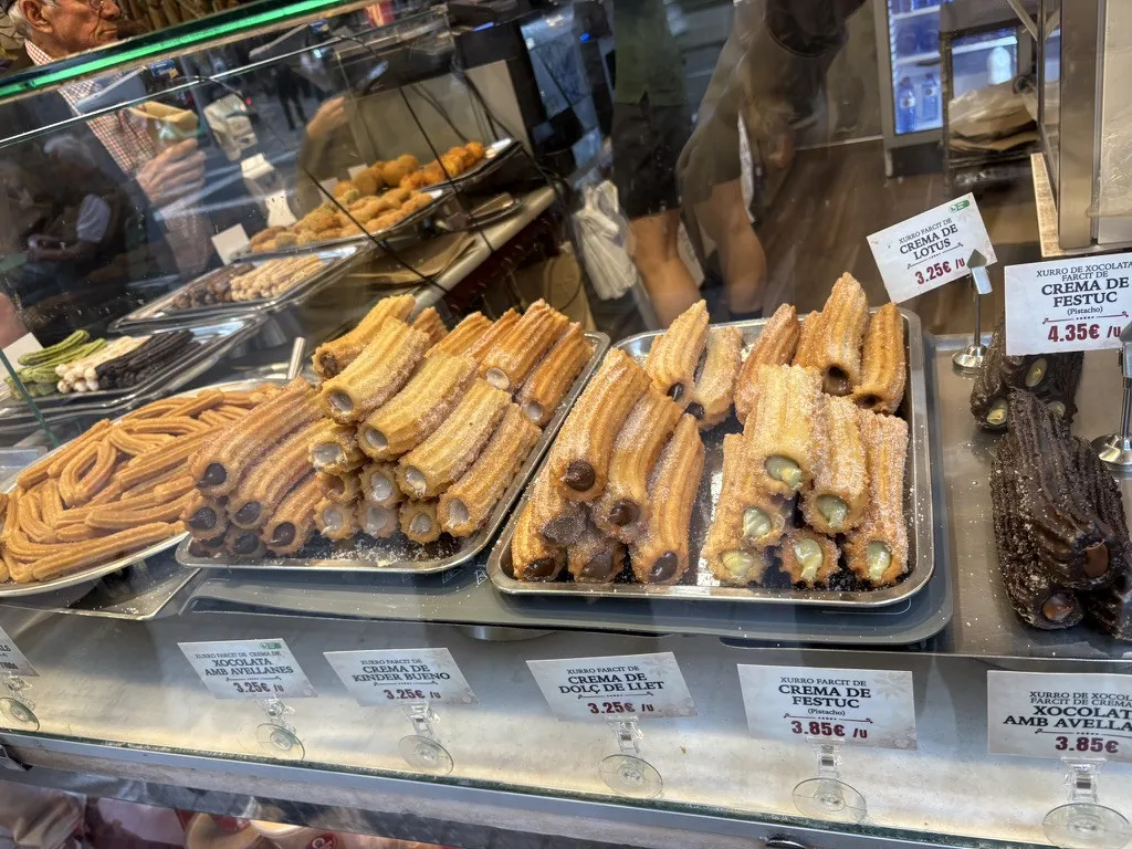 Filled churros in the display case, with the price of each filling.