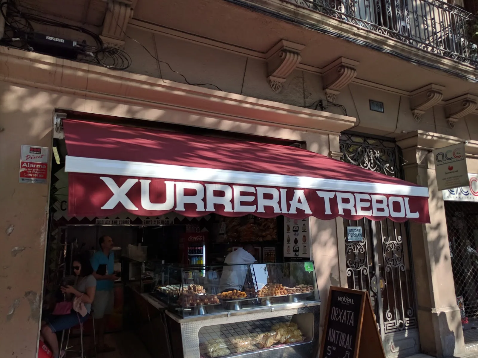 The front of Xurreria Trébol on Carrer de Còrsega, with its maroon awning and the counter open to the street.